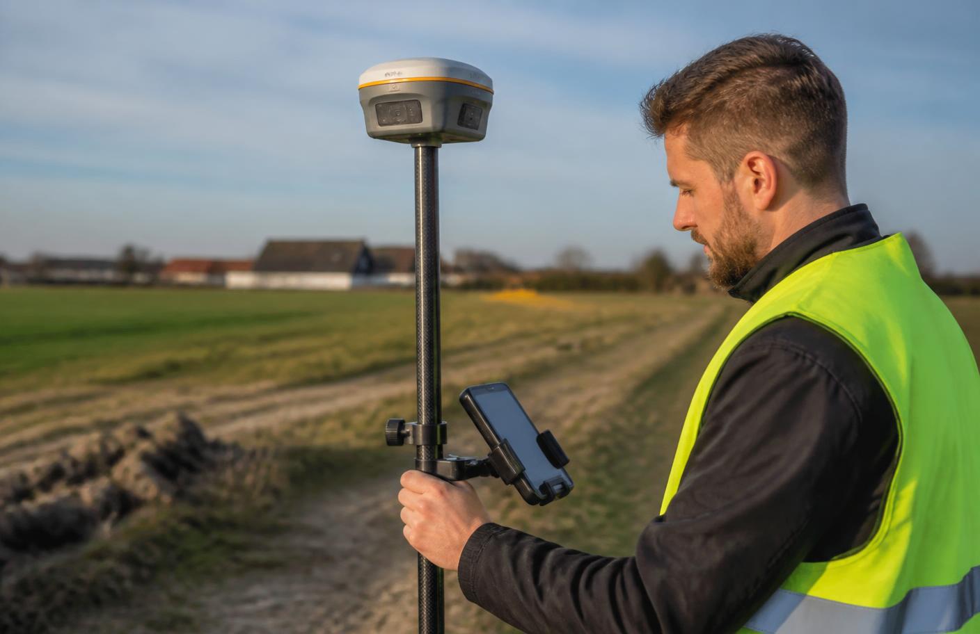 Geodeta z odbiornikiem GNSS RTK podczas pomiaru na działce